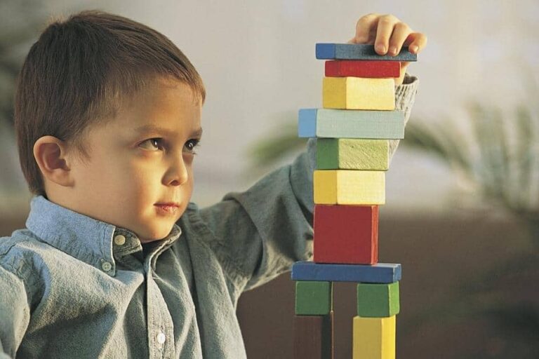 Дете учи чрез действия как се реди кула от кубчета
