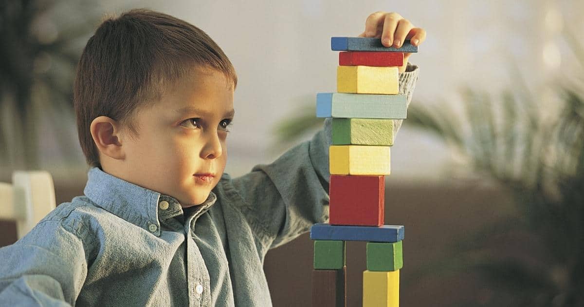 Дете учи чрез действия как се реди кула от кубчета