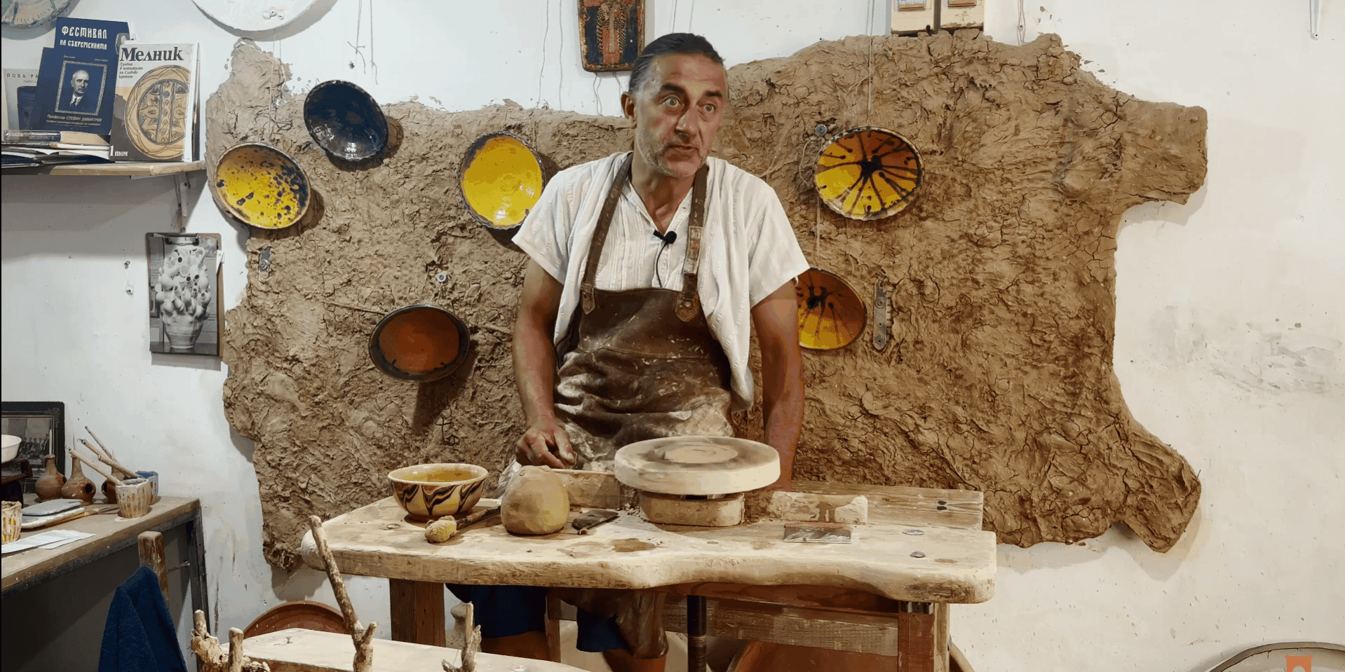 Майстор- грънчар Захари Иванов в своето ателие. На стената има карта на България от глина