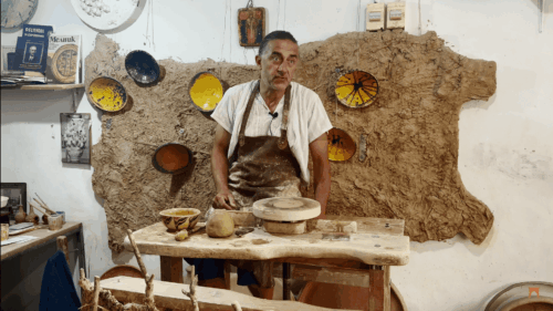 Майстор- грънчар Захари Иванов в своето ателие. На стената има карта на България от глина