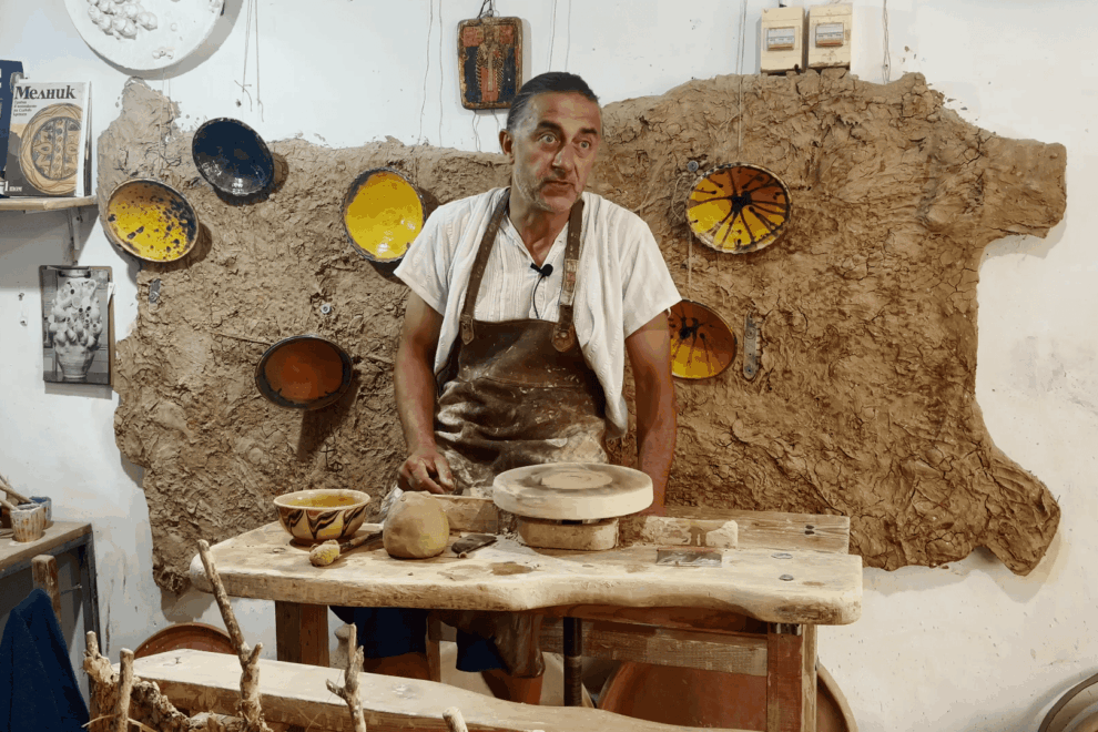 Майстор- грънчар Захари Иванов в своето ателие. На стената има карта на България от глина